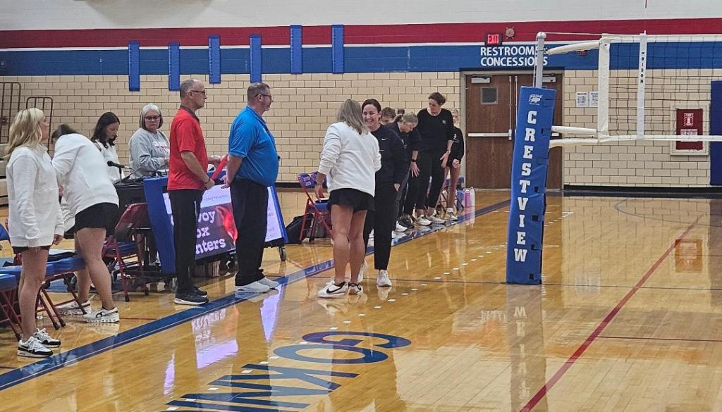 Crestview Lady Knights volleyball team preparing for a match with coaches and players on the court.