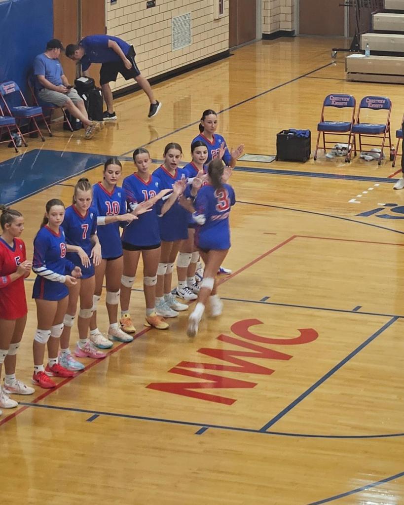 Crestview Lady Knights volleyball team lineup, featuring players in blue jerseys, preparing for a match on the court.