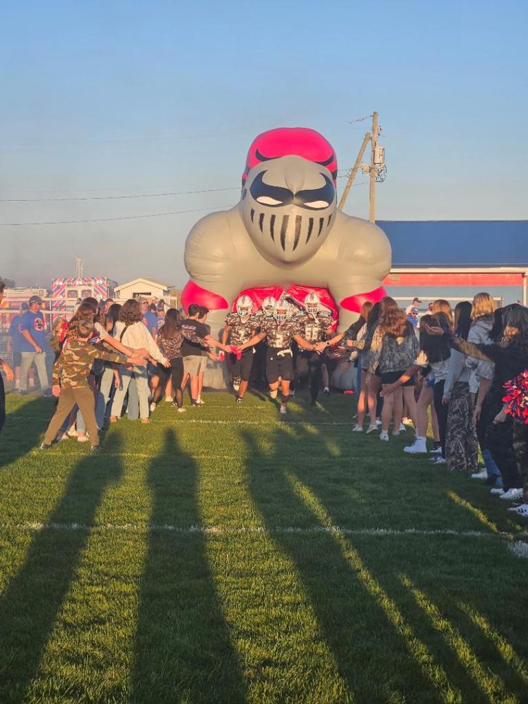 The Crestview Knights football team runs through an inflatable player tunnel during the pregame festivities on Military Appreciation Night.