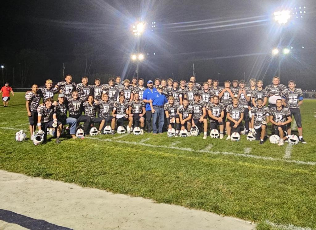 Crestview Knights football team poses together on the field after Military Appreciation Night, wearing special camouflage uniforms.