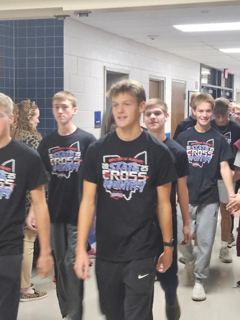 Crestview Knights boys' cross country team walking through the school hallway, wearing matching black shirts with a state championship logo.