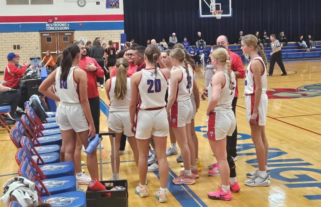 The Crestview Lady Knights basketball team huddled together, discussing strategy during a game against the Fort Jennings Lady Musketeers in the gymnasium.